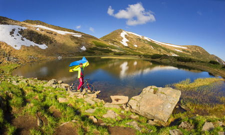 Ukraine, Verkhovyna, 29 May 2016:Racer bicycle on the lake reservoir Nesamovyte highest Carpathians and Ukraine among the snow against the backdrop of mountain ranges and peaks in the glow of dawn greets the new dayのeditorial素材