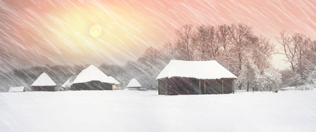 After sunset, the traditional Ukrainian village began snowfall and blizzards, snowdrifts pout and covered the roads and footpaths. Thick forest and gardens beautiful pattern on the background of skyの写真素材