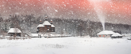 After sunset, the traditional Ukrainian village began snowfall and blizzards, snowdrifts pout and covered the roads and footpaths. Thick forest and gardens beautiful pattern on the background of skyの写真素材