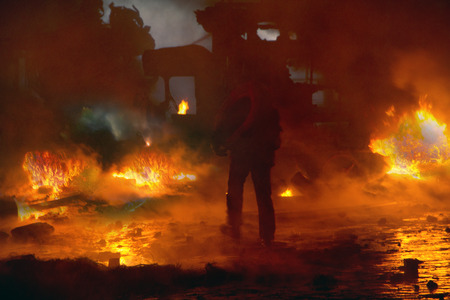 Kiev, Ukraine - January 22, 2014: Among the flame burning wheels rebel fighters try to contain the...