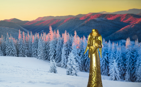 The sacred ancient religious sculpture on a Christmas theme background winter mountain landscape in Ukraine Carpathian spruce tops and cold wilderness of Eastern Europeの写真素材