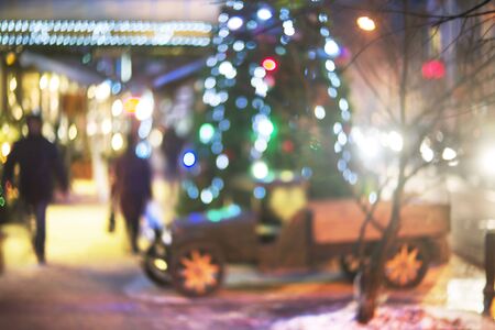 Evening city picture with defocused effect blur Lenses gives lightness and fabulousness. Illumination and fabulous silhouette of people going shopping for Christmasの写真素材