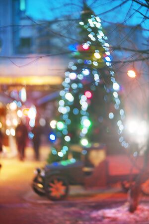 Evening city picture with defocused effect blur Lenses gives lightness and fabulousness. Illumination and fabulous silhouette of people going shopping for Christmasの写真素材