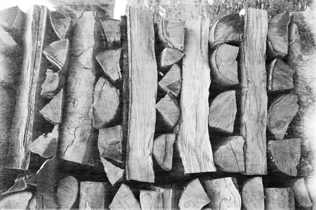 An old film black-and-white image. Warehouse a stack of cut chopped sawn natural firewood in a...