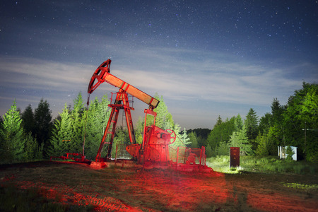ancient traditional classic oil pumps of Ukrainian oilmen in the Carpathian Mountains on the Delyatyn Polonium are illuminated by colored LED flashlights under the starry sky of the Galaxyの写真素材