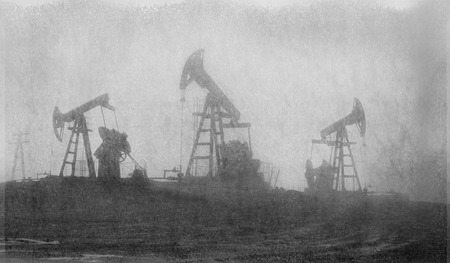 An old film black-and-white image of oil production in America USA. pumps rocking at dawn amid the damaged ecology of alpine meadows work to produce the energy of the modern worldの写真素材