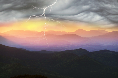 Evening sunset in the Carpathians over the Vorokhta and Yasinya Ukraine valley brightly painted paints over the dark mountains and ridges of Gorgan and the glowing lights of housesの写真素材