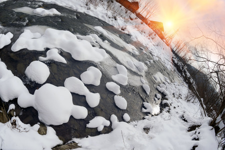 First snow in the Ukrainian Carpathians frozen river, beautiful forms bumps shining sun beams soft light effects with the picturesque hills of wild snow after a snow storm and blizzardの写真素材
