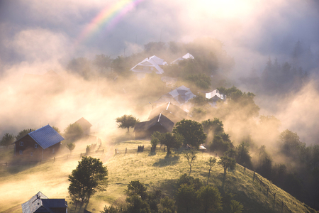 dawn in the mountains is fabulous and beautiful, the waves of the misty sea float in the valley against the background of high peaks covered with forests. At the bottom of the mountain villageの写真素材