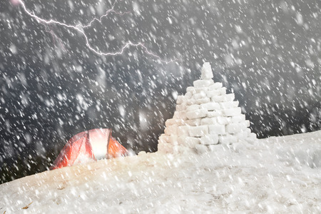 At the top of the wild mountain climber built a snow shelter to rescue from the storm. The icy...