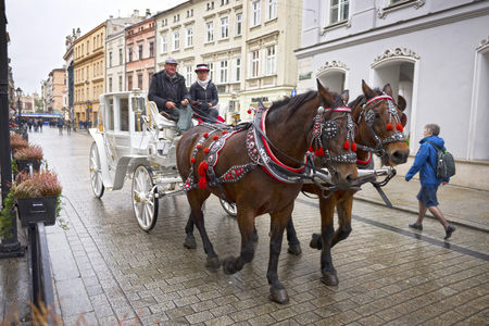 Poland, Krakow, September 14, 2015: Guests of the city, tourists and travelers, townspeople ride on carriages and horses in the ancient Market Square, the main sight of the cityのeditorial素材