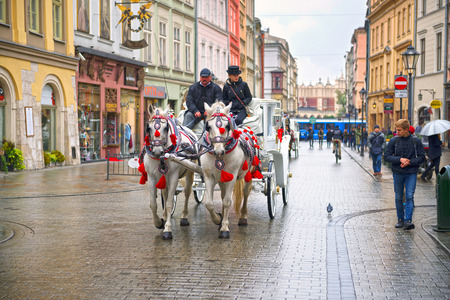 Poland, Krakow, September 14, 2015: Guests of the city, tourists and travelers, townspeople ride on carriages and horses in the ancient Market Square, the main sight of the cityのeditorial素材