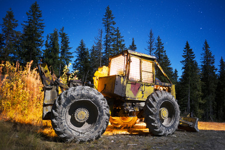 An ancient tractor at the top of the mountain for transportation of coniferous forest is illuminated by a photographer of various lights in the moonlit night in the Carpathians as an art objectの写真素材