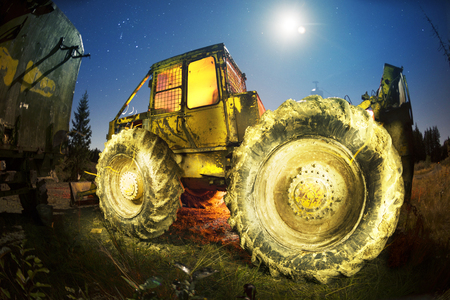 An ancient tractor at the top of the mountain for transportation of coniferous forest is illuminated by a photographer of various lights in the moonlit night in the Carpathians as an art objectの写真素材