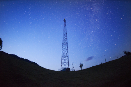 a trip in the mountains at night near the mobile signal tower tower in Ukraine in the Carpathians Ukraine. Metal red design against the background of a huge starry sky is very beautifulの写真素材