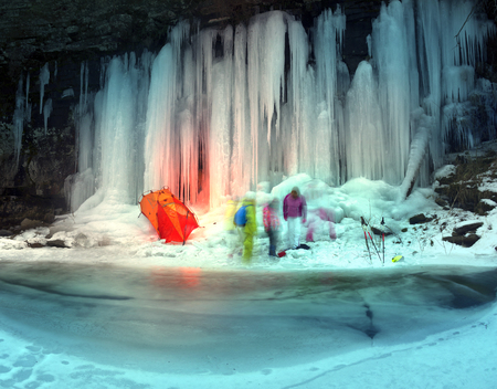 Alpine wild canyon in severe frost streams of water froze on high vertical rocks and tourists...