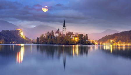 Night view of the town of Bled with a picturesque island among the lake, a castle on a rocky cliff and the outlines of the Julian Alps in the background - all this creates a stunning landscape.のeditorial素材