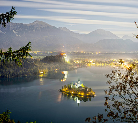 Night view of the town of Bled with a picturesque island among the lake, a castle on a rocky cliff and the outlines of the Julian Alps in the background - all this creates a stunning landscape.のeditorial素材