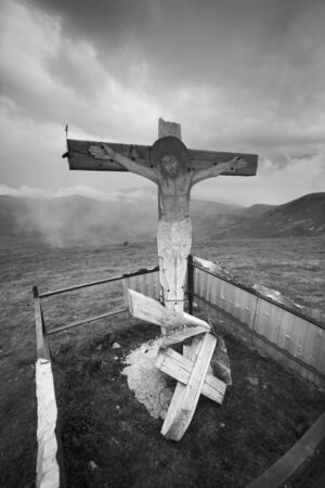 wooden cross in the Carpathians after a thunderstorm with lightning and thunder over the tops of the ridges, with strong wind and rain - there comes a clear beautiful morningの写真素材