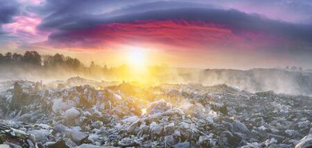 beautiful foggy dawn of the Sun over a huge field of urban garbage, saturated with poisonous fumes of decomposition of organic waste and household chemicalsの写真素材