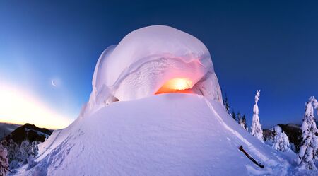 snow cornice at the top is a snow formation formed in the mountains under the influence of wind. Artistic illumination lamp has created a fabulous fiction pictureの写真素材