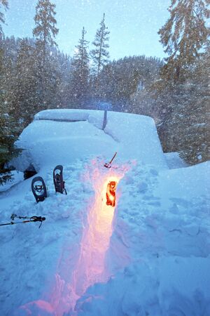 An avalanche mountain shelter in the American mountains. Alpine lifeguards dig up the entrance to a...