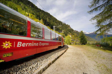 Switzerland, Poschiavo, October 10, 2019: Railroad train on the shore of Lake Poschiavo against the backdrop of alpine peaks. It connects the cities of St. Moritz in the canton of Graubunden, Switzerland and Tirano, in the province of Sondrio, Italy, throのeditorial素材