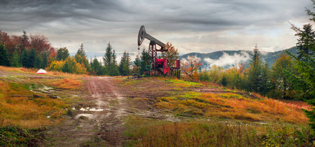 Oil gas traditional old pump platform for mining production of minerals - oil and gas in the autumn mountains of Europe after rain and fog.の写真素材
