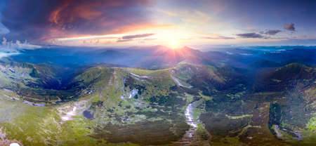 The drone flies over the peaks after the rain over the Chornohora ridge and the Hoverla Goverla peak at a high altitude, the picturesque rays of the sun illuminate the panorama. Mount Turkul and Hoverla, Lake Nesamoviteの写真素材