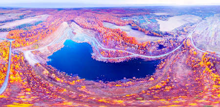 A large clay pit for the production of bricks, with a clean lake in the middle of a beautiful autumn forest in Ukraine. Aerial photo drone copter photo from a bird's eye view.の写真素材