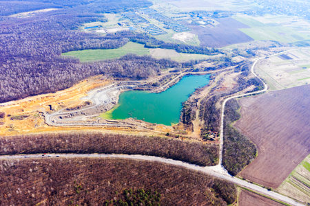 Aerial photo from a drone copter to a clay pit with a lake and excavators. In the middle of a wild...