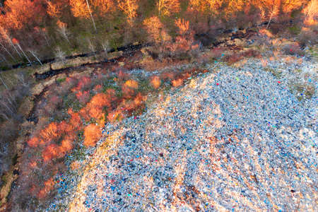 Aerial footage with a modern drone quadcopter shows the global scale of recycling European urban waste in the wild forest, primarily plastic polymerの写真素材