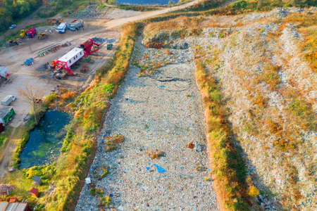 The autumn forest is beech and coniferous, among which there is a landfill of a large European city, a processing plant, and a gypsy village. Aerial view drone copterの写真素材
