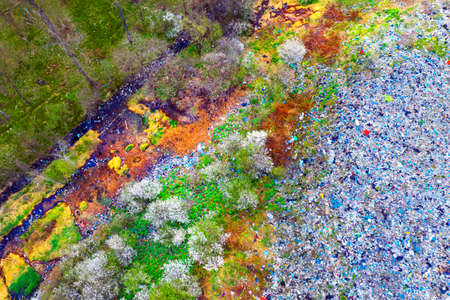 Aerial photo from a drone copter to a toxic waste dump in the city. Amid this ecological disaster, cherry plum and blackthorn bushes blossomed in the spring, creating a contrast between life and death.の写真素材