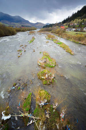 Environmental disaster in Transcarpathia, Ukraine. Residents of mountain villages throw plastic waste directly into the rivers, which bring it to the reservoir and dump it on its banks. Low ecology. Flight aerial photo drone quadcopterの写真素材