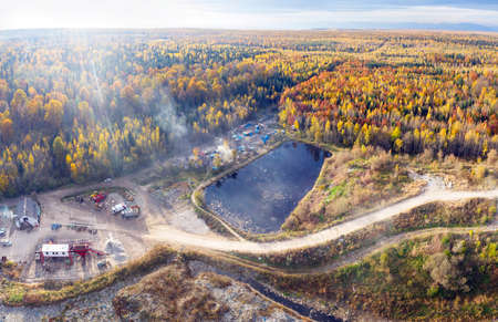 The autumn forest is beech and coniferous, among which there is a landfill of a large European city, a processing plant, and a gypsy village. Aerial view drone copterの写真素材
