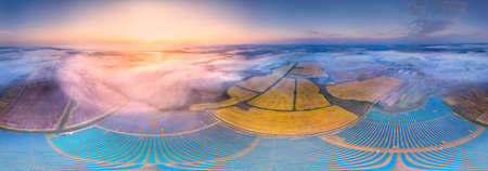 Sunrise in Ukraine, Europe over the field of an ecologically clean source of electrical energy - solar panels. Waves and sea of ââscenic fog give a fabulous magical effectの写真素材
