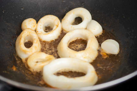 chef grilling seafood on frying pan in dark restaurantの写真素材