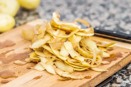 Potato peels on a horizontal wood in a kitchen of a house.Concept of preparing an traditional spanish omeletteの写真素材
