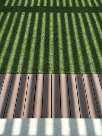 Strip shadow on green grass, wood and cement floorの素材