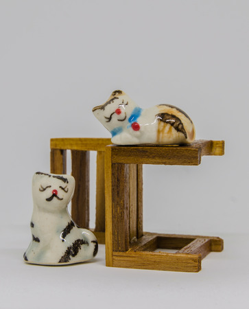 The cat is lying on the other nine crouched cats, sitting next to the same chair on a white background.の写真素材