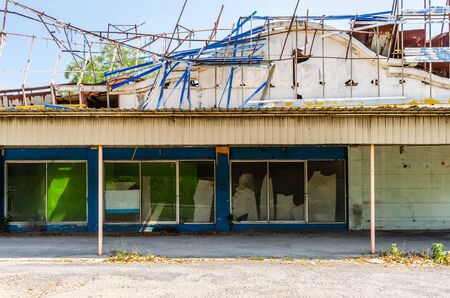 A long low decrepit old shed with rusted iron roof against a blue sky background In the tropicsの写真素材