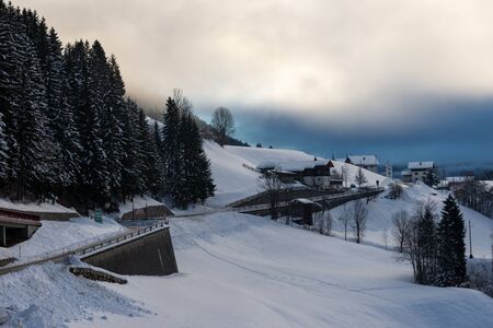 village in the alps underneath dark low cloudsの写真素材