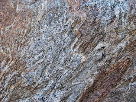 folded bands of brown and gray gneiss rock