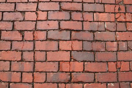 surface of an old red brick road showing cracked bricks suitable for background