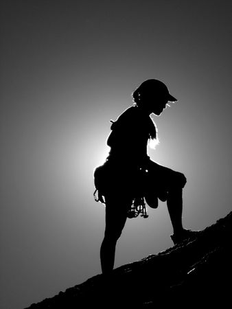 black and white silhouette of a woman climber nearing the summit blocking the sun with diffraction lighting around herの写真素材