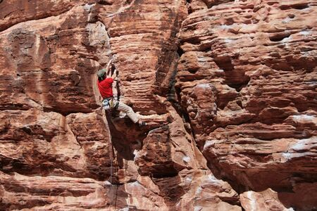 rock climber in red climbing a red sandstone cliff at Red Rocks, Nevadaの写真素材