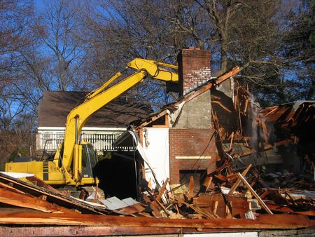 a yellow excavator demolishes a houseの写真素材