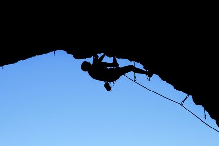 silhouette of rock climber climbing on a steep roofの写真素材