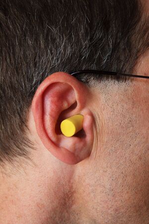 a man's ear with yellow foam earplug